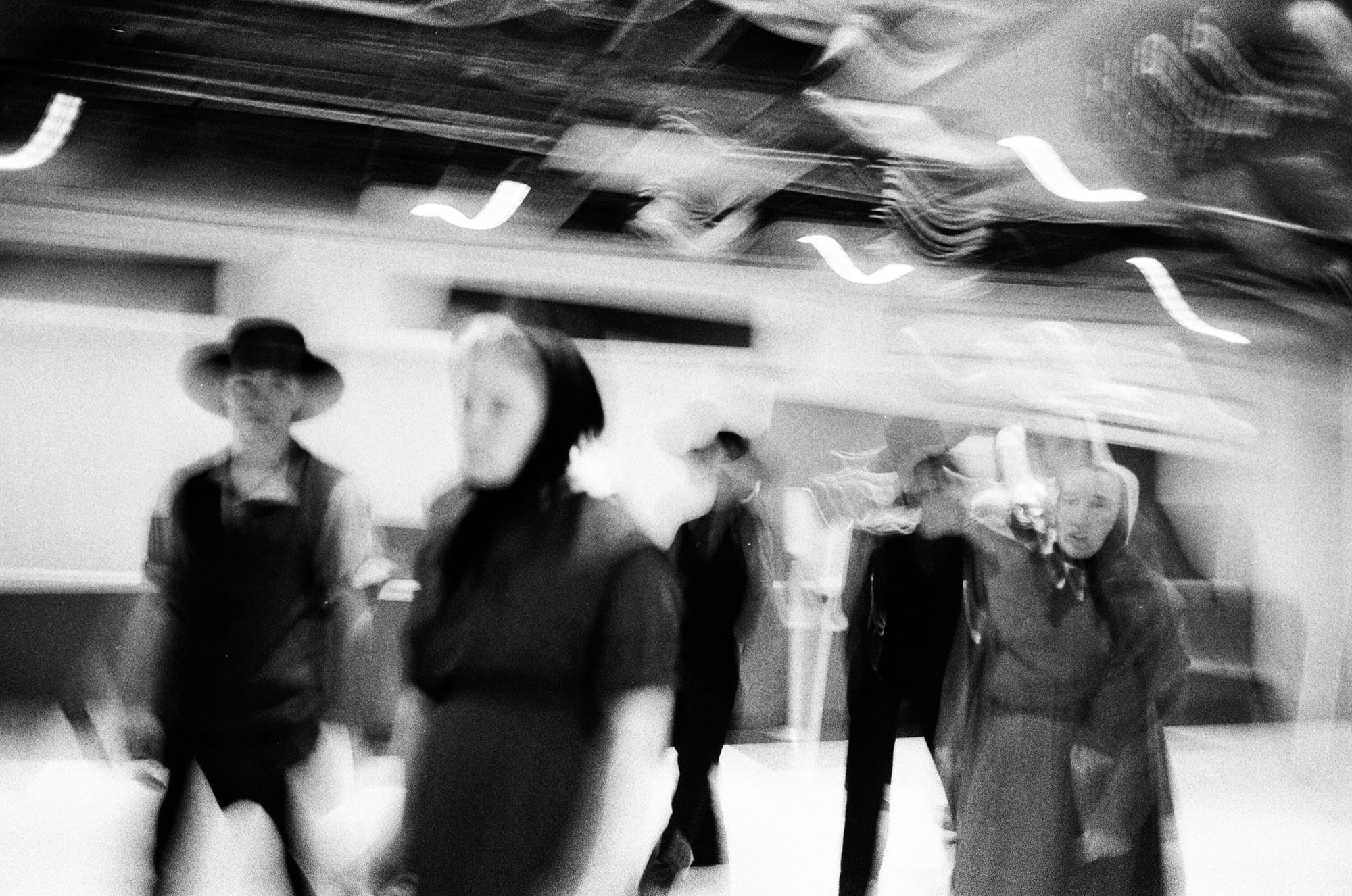 A black and white photo with significant motion blur, of a group of people in Amish or Mennonite garb, several looking at the camera